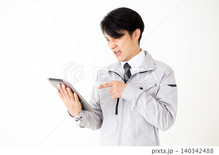 タブレットを見て驚くグレーの作業着のミドル男性ビジネスマン白バック 140342488