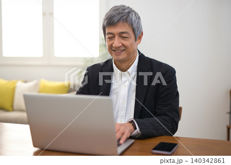ノートパソコンで作業をするジャケットを着た60代男性 140342861