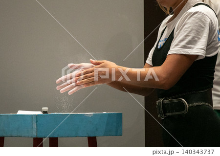 Female powerlifter applies talcum powder to her hands 140343737