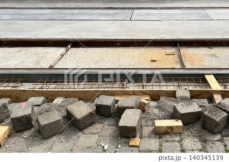 Road and tram track reconstruction in Vienna, Austria. Construction site with exposed reinforcement bars, paving stones, gravel and infrastructure repair work Road and tram track reconstruction in Vienna, Austria. Construction site with exposed reinforcement bars, paving stones, gravel and infrastructure repair work 140345139