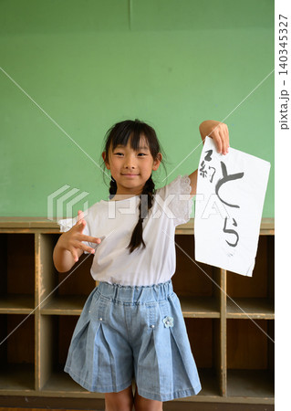 教室の後ろで笑顔で「とら」の習字作品を高く掲げる女子小学生 教室の後ろで笑顔で「とら」の習字作品を高く掲げる女子小学生 140345327