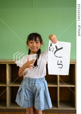 教室の後ろで笑顔で「とら」の習字作品を高く掲げる女子小学生 教室の後ろで笑顔で「とら」の習字作品を高く掲げる女子小学生 140345328