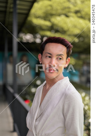 Vertical close up portrait of non-binary gay Thai man looking away on covered outdoor walkway Vertical close up portrait of non-binary gay Thai man looking away on covered outdoor walkway 140345478