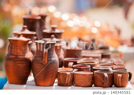 Handcrafted pottery displayed at a local market with warm sunlight illuminating the vibrant colors Handcrafted pottery displayed at a local market with warm sunlight illuminating the vibrant colors 140345581
