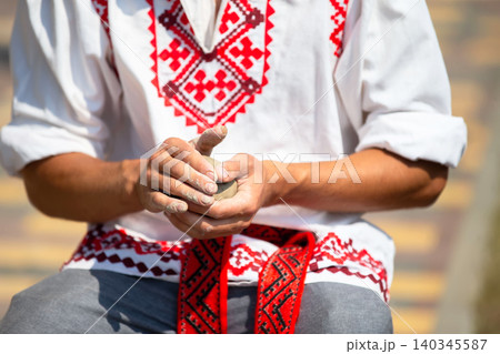 Craft clay, wearing traditional Slavic clothing in a bright open area in the daytime Craft clay, wearing traditional Slavic clothing in a bright open area in the daytime 140345587
