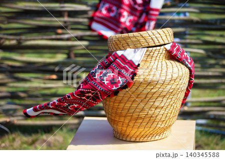Handcrafted wicker vase adorned with traditional textile in a rural setting during daylight 140345588