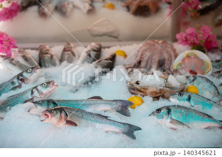 Fresh seafood display featuring various fish, shellfish, and octopus at a market in a coastal town during daylight hours Fresh seafood display featuring various fish, shellfish, and octopus at a market in a coastal town during daylight hours 140345621