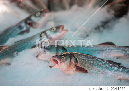 Fresh fish displayed on ice at a bustling market in the early morning sunlight 140345622