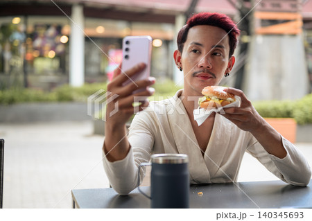 Thai Non-Binary Gay Man Taking Selfie with Burger Outdoors Thai Non-Binary Gay Man Taking Selfie with Burger Outdoors 140345693