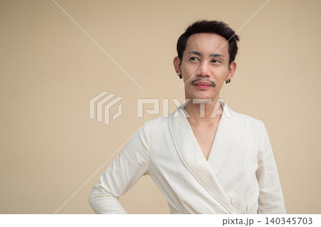Thai Non-Binary Gay Man Thinking and Looking Away against Plain Wall Thai Non-Binary Gay Man Thinking and Looking Away against Plain Wall 140345703