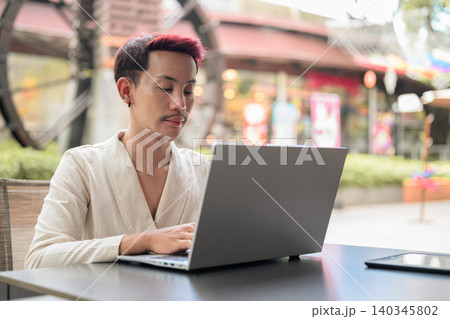 Thai Non-Binary Gay Man Working on Laptop Outside Cafe Thai Non-Binary Gay Man Working on Laptop Outside Cafe 140345802