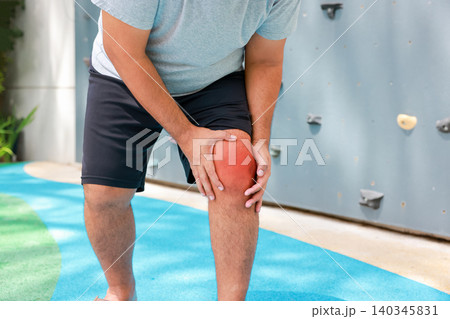 Close up of unrecognizable man suffering from knee joint pain with glowing red graphic overlay on his leg. Muscle cramp, sports injury and medical healthcare concept. Close up of unrecognizable man suffering from knee joint pain with glowing red graphic overlay on his leg. Muscle cramp, sports injury and medical healthcare concept. 140345831