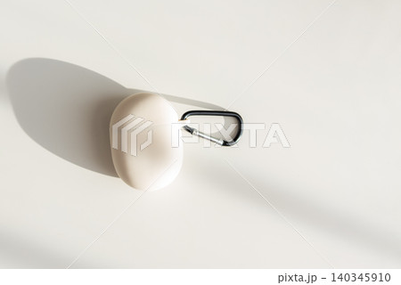 Beige wireless earbuds case with carabiner on white background Beige wireless earbuds case with carabiner on white background 140345910
