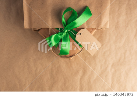 Craft gift box with green ribbon and blank tag in a bag Craft gift box with green ribbon and blank tag in a bag 140345972