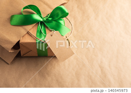 Gift box with green ribbon and blank tag on paper background Gift box with green ribbon and blank tag on paper background 140345973