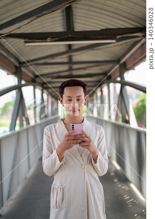 Vertical Portrait of Thai Non-Binary Gay Man Texting on Footbridge Vertical Portrait of Thai Non-Binary Gay Man Texting on Footbridge 140346028