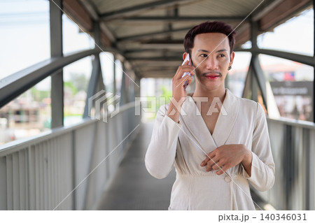 Thai Non-Binary Gay Man Making Phone Call on Covered Footbridge Thai Non-Binary Gay Man Making Phone Call on Covered Footbridge 140346031