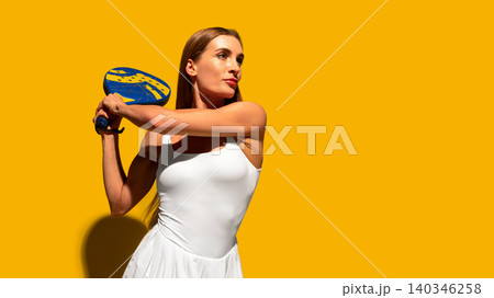 Female padel player holding racket on bright yellow studio background. Female padel player holding racket on bright yellow studio background. 140346258
