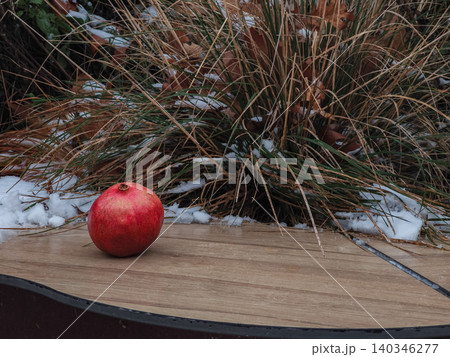 Pomegranate fruit resting on wooden surface with snow 140346277