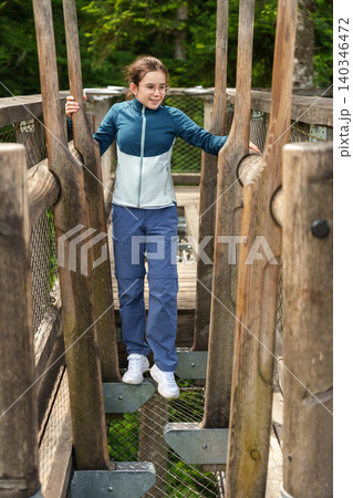 Girl walking through wooden obstacle at treetop adventure park 140346472