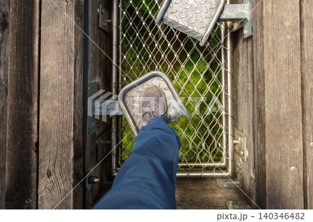 Foot stepping on metal platform in treetop adventure park Foot stepping on metal platform in treetop adventure park 140346482