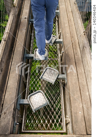 Foot stepping on metal platform in treetop adventure park Foot stepping on metal platform in treetop adventure park 140346484