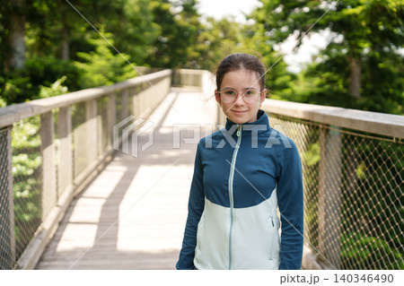 Girl walking on treetop walkway in forest adventure park Girl walking on treetop walkway in forest adventure park 140346490