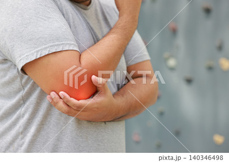 Close up of man suffering from elbow joint pain with glowing red graphic after rock climbing exercise. Sports injury, muscle inflammation and medical healthcare concept. Close up of man suffering from elbow joint pain with glowing red graphic after rock climbing exercise. Sports injury, muscle inflammation and medical healthcare concept. 140346498