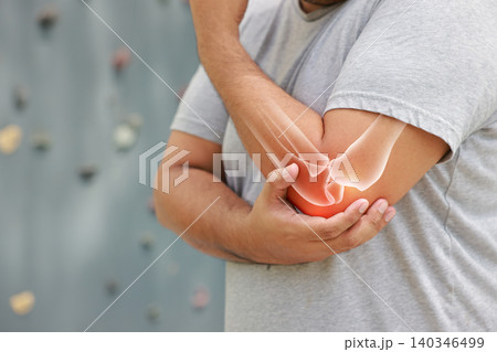 Close up of a man suffering from elbow joint pain with glowing bone anatomy graphic overlay after rock climbing exercise. Sports injury and medical healthcare concept. 140346499