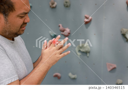 Overweight Asian man suffering from index finger joint pain with glowing red graphic overlay after rock climbing exercise. Sports injury, muscle inflammation and healthcare concept. Overweight Asian man suffering from index finger joint pain with glowing red graphic overlay after rock climbing exercise. Sports injury, muscle inflammation and healthcare concept. 140346515