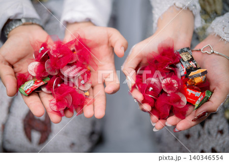 Traditional Wedding Souvenirs and Coins in the Hands of the Bride and Groom During an Indonesian Wedding Ceremony Traditional Wedding Souvenirs and Coins in the Hands of the Bride and Groom During an Indonesian Wedding Ceremony 140346554