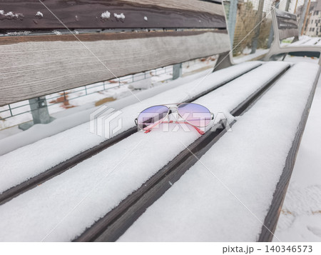Forgotten sunglasses resting on a snowy park bench Forgotten sunglasses resting on a snowy park bench 140346573