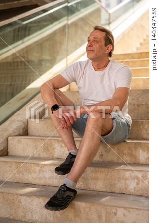 Portrait of a 55 year old man during a rest against urban architecture. Portrait of a 55 year old man during a rest against urban architecture. 140347589