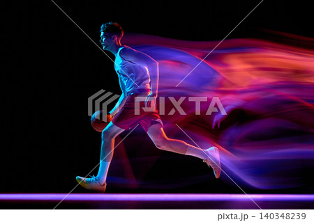 Basketball player running with ball and neon speed trails in dark studio Basketball player running with ball and neon speed trails in dark studio 140348239
