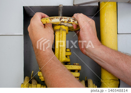 Energy crisis and gas supply management, hands turning yellow industrial valve for natural gas pipeline control and regulation. Energy crisis and gas supply management, hands turning yellow industrial valve for natural gas pipeline control and regulation. 140348814