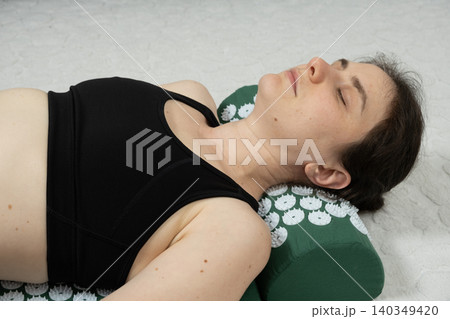 Woman Relaxing on Acupressure Mat and Pillow at Home Woman Relaxing on Acupressure Mat and Pillow at Home 140349420
