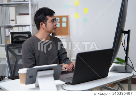 Focused Programmer Working on Code at a Desk Setup in a Professional Environment Focused Programmer Working on Code at a Desk Setup in a Professional Environment 140350497