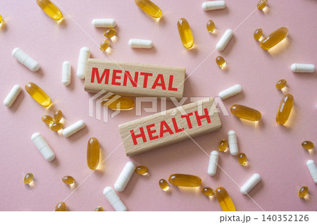 MENTAL HEALTH symbol. Concept word MENTAL HEALTH on wooden blocks. Beautiful pink background with pills. Medicine and MENTAL HEALTH. Copy space 140352126