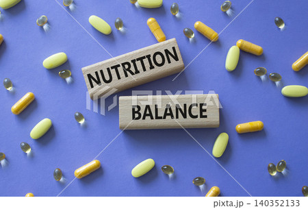 Nutrition Balance symbol. Concept word Nutrition Balance on wooden blocks. Beautiful purple background with pills. Medicine and Nutrition Balance. Copy space 140352133