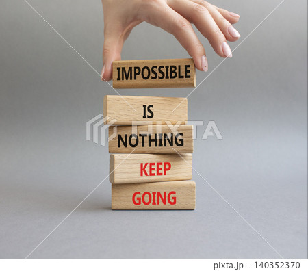 Keep Going symbol. Wooden blocks with words Impossible is Nothing Keep Going. Businessman hand. Beautiful grey background. Business and Keep Going concept. Copy space Keep Going symbol. Wooden blocks with words Impossible is Nothing Keep Going. Businessman hand. Beautiful grey background. Business and Keep Going concept. Copy space 140352370