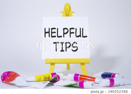 Helpful tips symbol. Wooden blocks with words Helpful tips. Beautiful white background with paints and easel. Business and Helpful tips concept. Copy space. 140352398