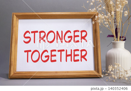 Stronger together symbol. Concept words Stronger together on beautiful wooden picture frame. Beautiful grey background with flower vase. Business and Stronger together concept. Copy space. Stronger together symbol. Concept words Stronger together on beautiful wooden picture frame. Beautiful grey background with flower vase. Business and Stronger together concept. Copy space. 140352406