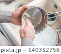 Man washes dishes in a kitchen sink 140352756