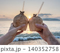 Two hands holding a fresh coconut with a straw 140352758