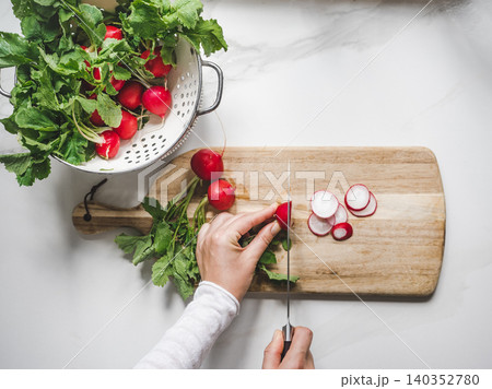 Hands slicing fresh red radishes Hands slicing fresh red radishes 140352780