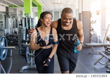 Young black laughing together in gym while checking smartphone after training Young black laughing together in gym while checking smartphone after training 140352964