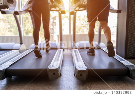 Rear view of young walking on treadmills in modern fitness center 140352998
