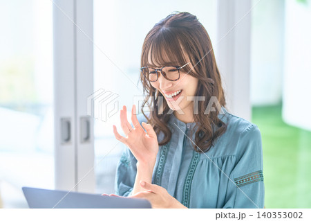 ノートパソコンに向かって笑顔で手を振る眼鏡の女性 140353002