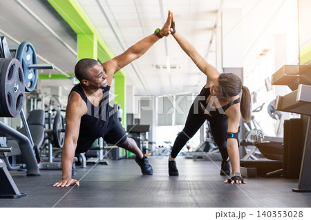 Black fitness giving high five while in push-up position on gym Black fitness giving high five while in push-up position on gym 140353028