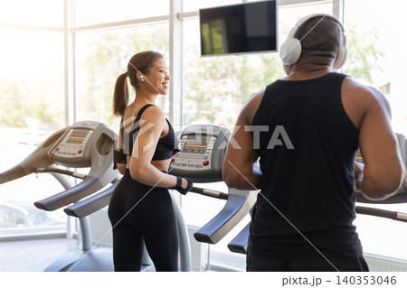Young black jogging on treadmills in spacious fitness center Young black jogging on treadmills in spacious fitness center 140353046